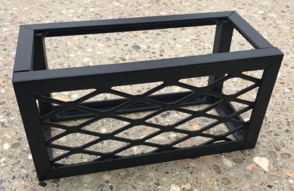 A black metal basket sitting on top of the ground.